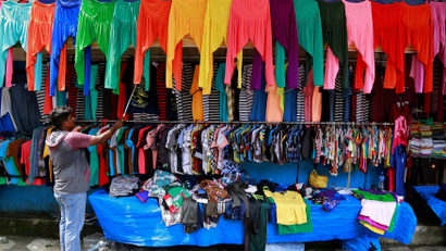 A vendor arranges clothes at his roadside shop in Kochi
