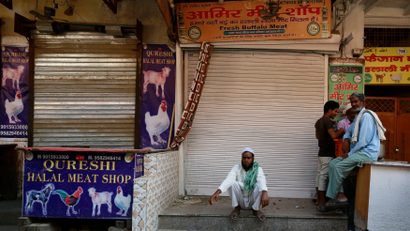 People sit outside the closed meat shops in Gurugram