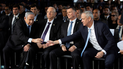 Netanyahu and Gantz reach out to shake hands.