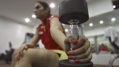 India's badminton player Gutta holds dumbbellwhile taking break during her exercise at gym in Hyderabad