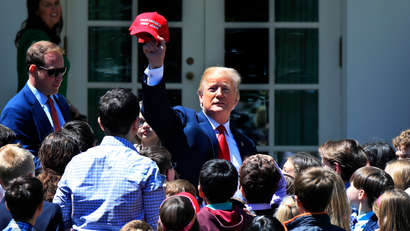 President Donald Trump surrounded by children of journalists and White House staff waves, a Make America Great Again cap, on the Rose Garden in celebration of "Bring Our Daughters and Sons to Work Day" at the White House in Washington, Thursday, April 26, 2018. (AP Photo/Manuel Balce Ceneta)