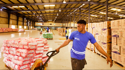 A warehouse worker pulling a cart stacked with goods