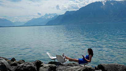 Woman reads a book on a warm spring day on the shore of Lake Leman in Vevey