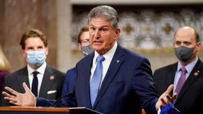 Joe Manchin spreads his arms wide while addressing reporters at the Capitol.