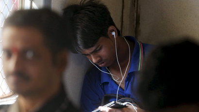 A man watches a video on his mobile phone as he commutes by a suburban train in Mumbai