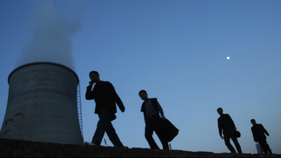 People walk on a street past a power plant's cooling tower in China.
