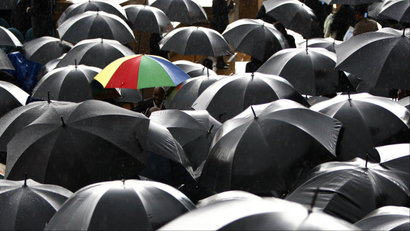 rainbow umbrella among black umbrellas