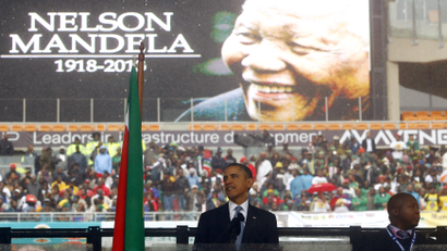 U.S. President Barack Obama gives a speech as a man passing himself off as a sign language interpreter (R) folds his hands during a memorial service for late South African President Nelson Mandela at the FNB soccer stadium in Johannesburg December 10, 2013.