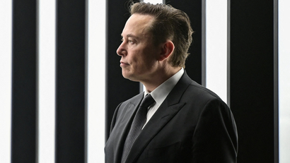 Side profile of Elon Musk wearing a black suit.