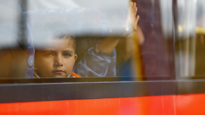 A migrant's child peers from a bus window near the border with Austria in Freilassing, Germany September 15, 2015. A total of 4,537 asylum seekers reached Germany by train on Monday despite the imposition of new controls at the border with Austria, the federal police said on Tuesday. The arrivals brought the number of asylum seekers who have entered Germany by train since the start of the month to 91,823, a police spokeswoman in Potsdam said. REUTERS/Dominic Ebenbichler