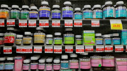 Rows and rows of vitamins and supplements on a pharmacy shop shelf.