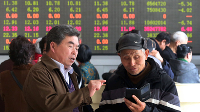 Investors talk in front of an electronic board showing stock informations at a brokerage house in Kaifeng, Henan province, April 9, 2015. China stocks lost ground on Thursday, as mainland investors rushed to buy relatively cheaper Hong Kong shares, but some key sectors such as property found support from bargain hunters. REUTERS/China Daily