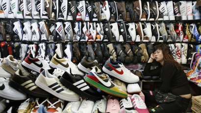 A shopkeeper selling counterfeit shoes waits for customers at stall in Beijing.