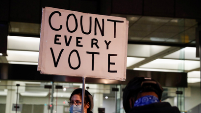 A person holds a sign reading "count every vote"