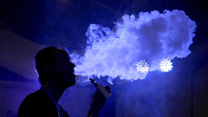 The silhouette of a man blowing a big puff of smoke against a purple background.