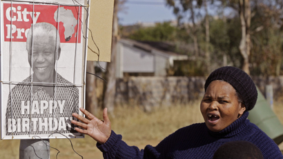 A woman reacts as she see a newspaper poster with a photo of former South African President Nelson Mandela on it in Mthatha, South Africa