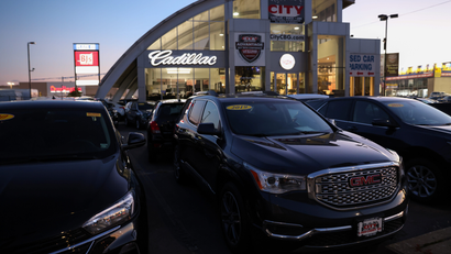 General Motors vehicles lined out outside of a dealership at dusk.