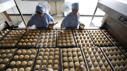 Freshly-baked mooncakes pass along a conveyor belt at a mooncakes factory in Shanghai September 12, 2013. With more calories than a Big Mac, mooncakes are traditionally given as gifts to family, friends and employees during China's Mid-Autumn Festival, which falls on Sept. 19 this year. But an anti-corruption drive by President Xi Jinping has left the pricier treats languishing on the shelves, shopkeepers and analysts say, even as sales of more traditional lotus seed- and sesame paste-stuffed varieties remain unhurt. Picture taken September 12, 2013.