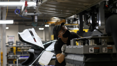 A worker looks to marry the body structure with the battery pack and the front and rear sub frames as they assemble electric vehicles at the Lucid Motors plant in Casa Grande, Arizona, U.S.