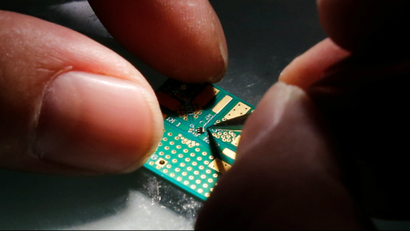 A researcher plants a semiconductor on an interface board during a research work to design and develop a semiconductor product at Tsinghua Unigroup research centre in Beijing, China,