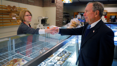 Mike Bloomberg shakes a woman's hand in a bakery in New Hampshire, an early voting state.