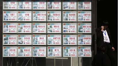 A man stands next to a board advertising apartments for sale or rental at a real estate agency in Beijing February 27, 2014. China's major lenders have not tightened or halted their property-related lending business, the official Xinhua news agency said, after local media reported that some banks had stopped lending to real estate developers. china housing property evergrande longfor greenland slump mortgage REUTERS/Kim Kyung-Hoon