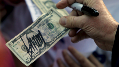 Trump hands a five-dollar bill back to a supporter after signing it, Feb 2016