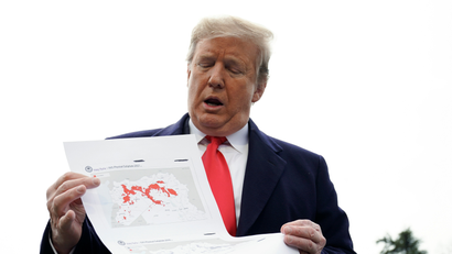 U.S. President Trump shows maps of Syria and Iraq as he departs the White House in Washington