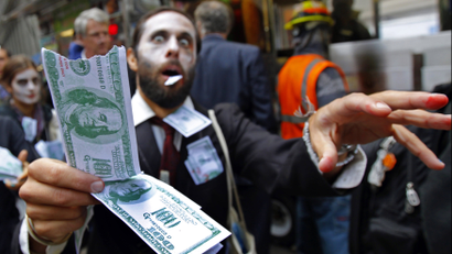 A demonstrator holds play money while dressed as a "corporate zombie" as he walks with others taking part in an Occupy Wall Street protest in lower Manhattan.