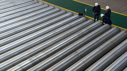 Workers check on seamless steel pipes at a steel factory in Hebei province, China