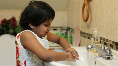 A girl washing her hands in a sink.