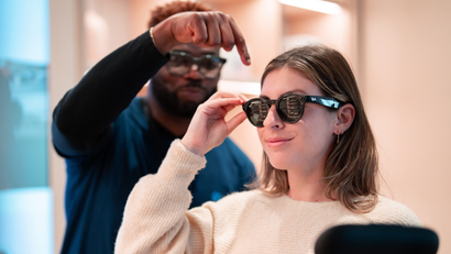 A Meta employee helping a user try on Ray-Ban Stories smart glasses
