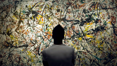 A person looks at a Jackson Pollock painting in an art gallery