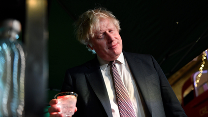 Boris Johnson holds a glass of gin with his head tilted to the side.