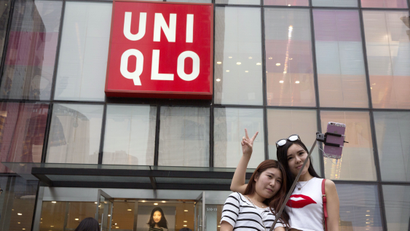 Chinese women take a selfie outside the Uniqlo flagship store where a steamy video purportedly taken inside one of its fitting room showing a couple apparently having sex in Beijing, Thursday, July 16, 2015. While online searches for the Japanese clothing brand soared after the viral spread of the video, it has also drawn the concern of the police and China's highest web regulator who are investigating whether it was a vulgar marketing gimmick.