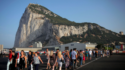 Pedestrians cross the tarmac at Gibraltar International Airport in front of the Rock near the border with Spain in the British overseas territory of Gibraltar