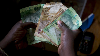 A shopkeeper counts out change above her cash box at her shop in Durban, South Africa.