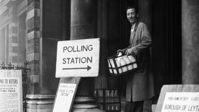 It was just striking seven o’clock when milkman Bill Hughes delivered the milk at Leyton Town Hall in London on Oct. 8, 1959. He left he milk on the Town Hall steps and went in to the polling station to cast his ballot along with the early voters. (AP Photo)