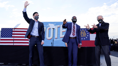U.S. President-elect Joe Biden points to Democratic U.S. Senate candidates from Georgia Jon Ossoff and Raphael Warnock onstage in front of a banner that says "Vote."
