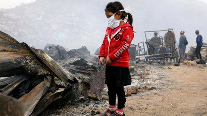 A child stands at the scene of a fire at 'Cantagallo' shanty town in Rimac district of Lima, Peru