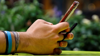 A person holds an iPhone an an e-cigarette