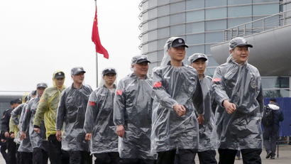 Security personnel wearing rain covers march at the paddock of the Shanghai International Circuit ahead of the Chinese Formula One Grand Prix at in Shanghai, China, Friday, April 7, 2017. The second practice session was canceled as the circuit's medical helicopter was unable to land at nearby hospitals or airports in case of an accident. (AP Photo/Toru Takahashi)