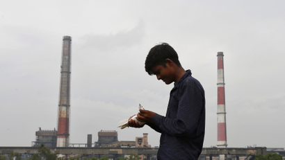 A boy examines a pigeon on a rooftop near a coal-fired power plant in New Delhi