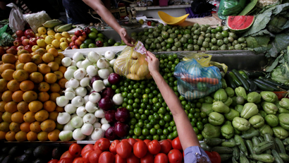 A woman buys vegetables at a market stall in Mexico City