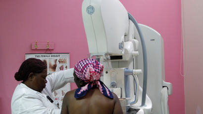 A radiographer prepares a patient to undergo a mammogram.