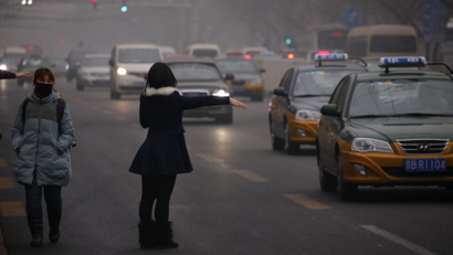 A woman sticks her hand out as she tries to grab the attention of a taxi driver on a hazy day of Beijing, January 30, 2013. Beijing temporarily shut down 103 heavily polluting factories and took 30 percent of government vehicles off roads to combat dangerously high air pollution, state media reported on Tuesday, but the capital's air remained hazardous despite the measures.