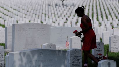 A woman carries red roses as she walks among graves on Memorial Day at Arlington National Cemetery in Washington
