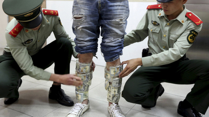 china dollar debt Paramilitary policemen take off U.S. dollars strapped around a man's legs, at the border of Hong Kong and Shenzhen, Guangdong province, April 24, 2014. According to local media, the man was found trying to smuggle in total US$580,000 from the mainland to Hong Kong. Picture taken April 24, 2014. REUTERS/China Daily