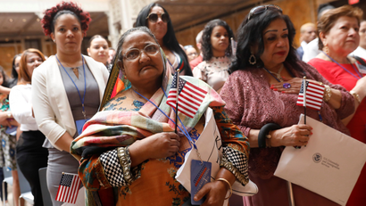 New citizens stand during a U.S. Citizenship and Immigration Services (USCIS) naturalization ceremony at the New York Public Library in Manhattan