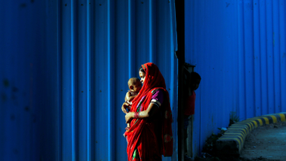 A woman day labourer holds her baby beside a construction site in New Delhi